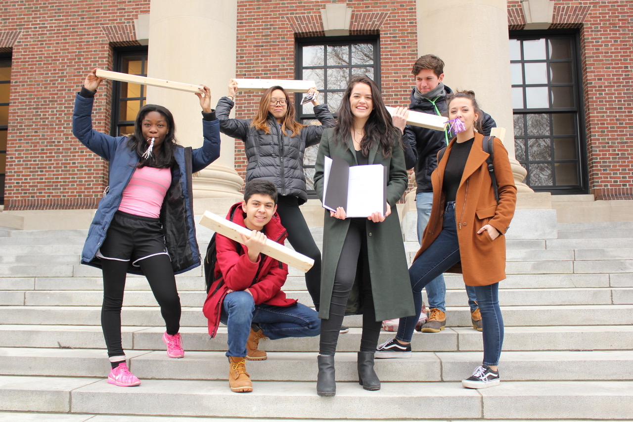 Friends holding decorated wooden paddles on outdoor steps