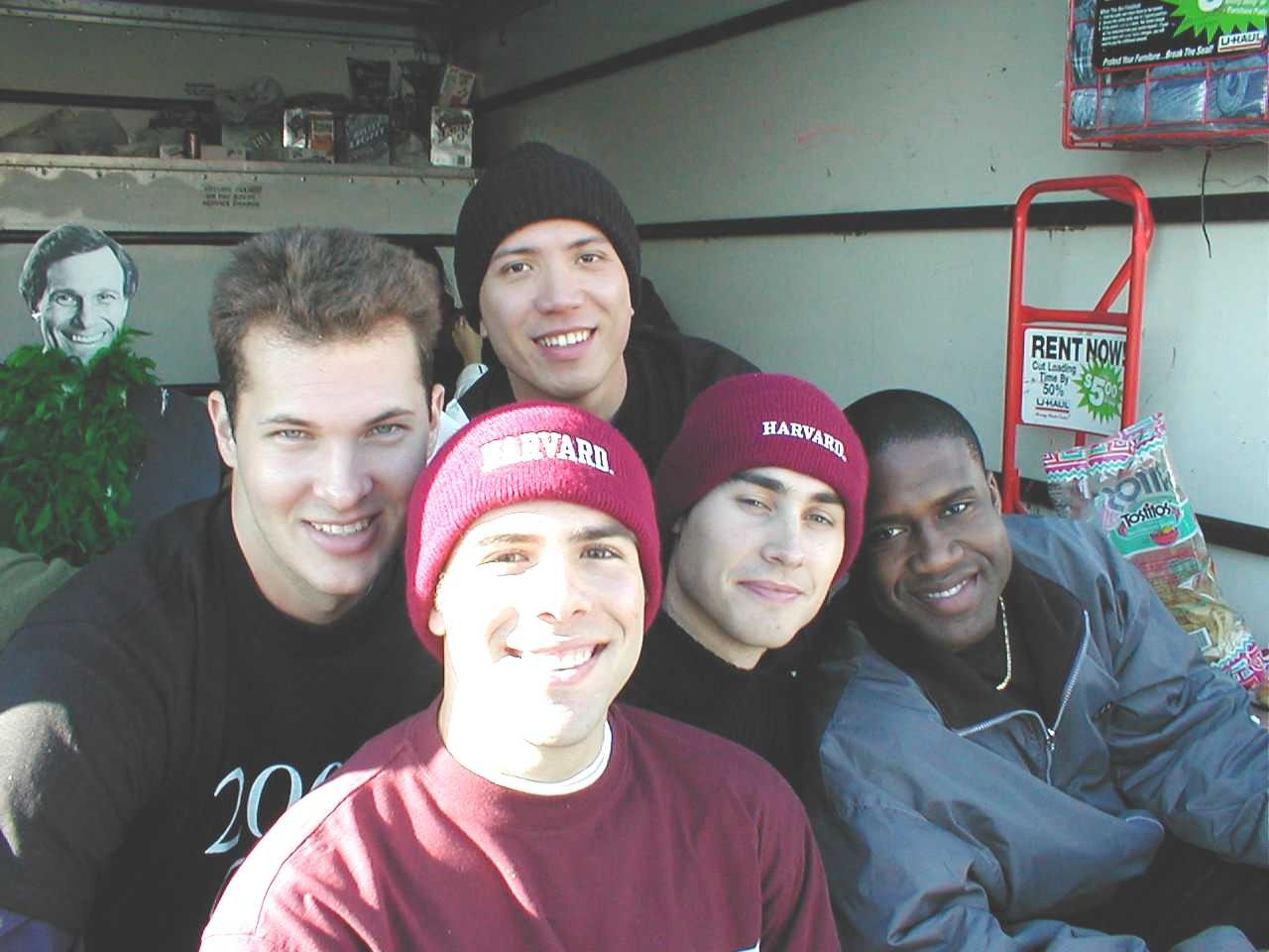 Friends smiling together in Harvard hats and sweatshirts