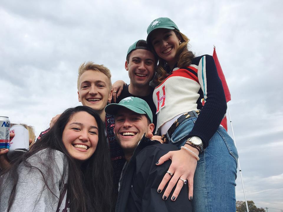 Friends wearing Harvard clothing gathered outdoors
