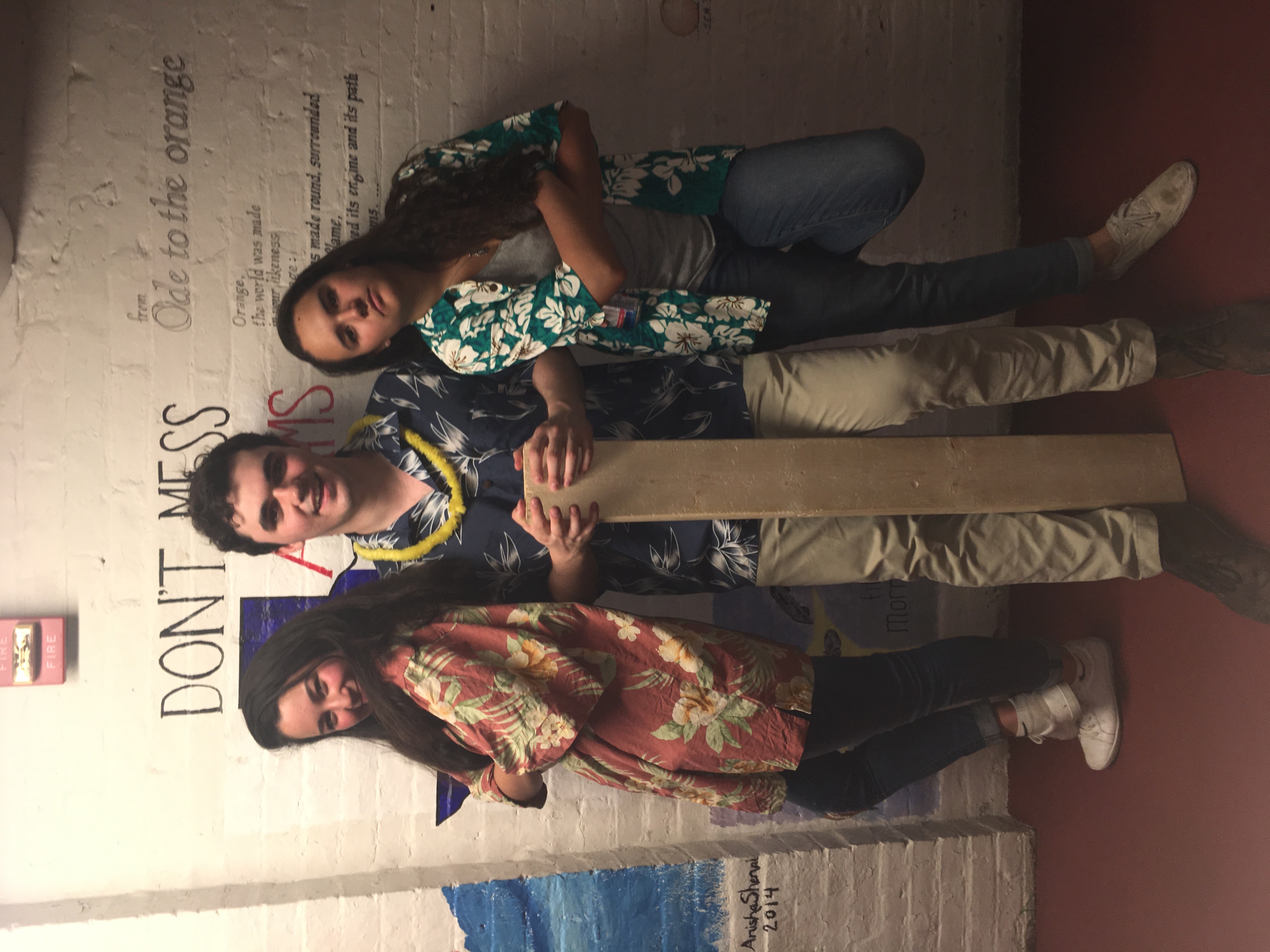 Three friends posing indoors with decorated wooden paddles