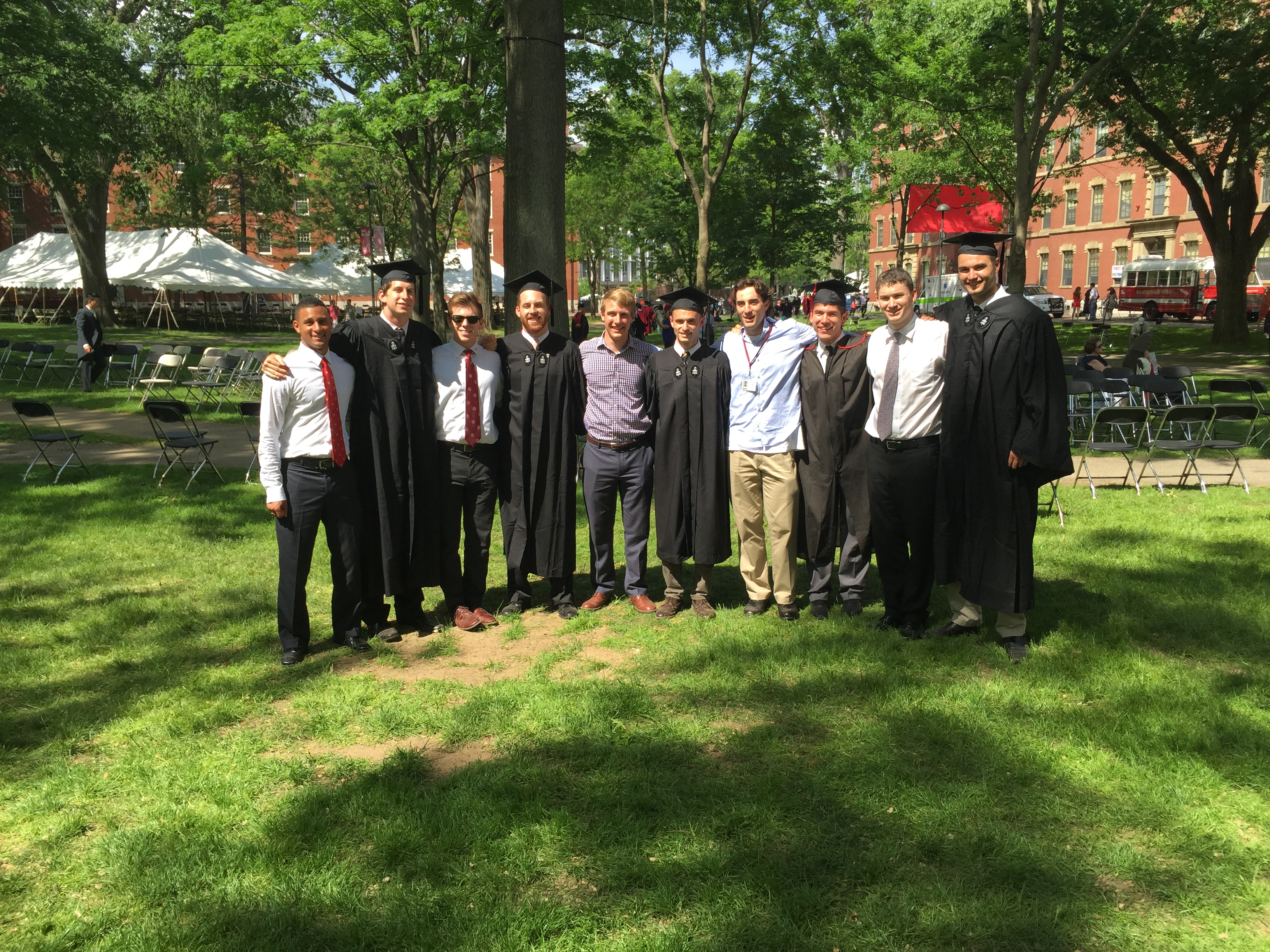 Friends posing together outdoors, several wearing graduation caps and gowns